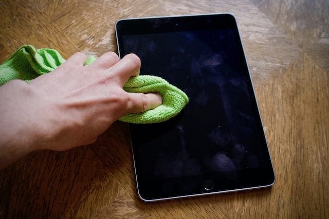 Cleaning a dirty iPad screen with a microfiber cloth.
