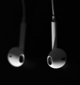 Photography of two Apple headphones hanging down with one side out of focus