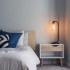 Photo of a minimalist bedroom showing a neat bed and a softly glowing bedside lamp
