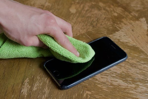 Photo of an iPhone being cleaned with a green microfibre cloth