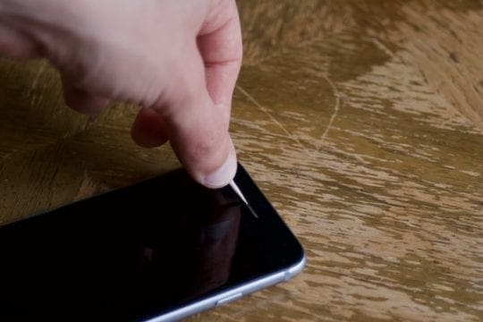 Photo of a toothpick being used to clean an iPhone speaker.