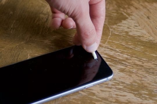 Photo of a rolled up piece of tape being used to clean an iPhone