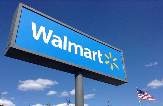 Walmart sign next to an American flag in front of a blue sky