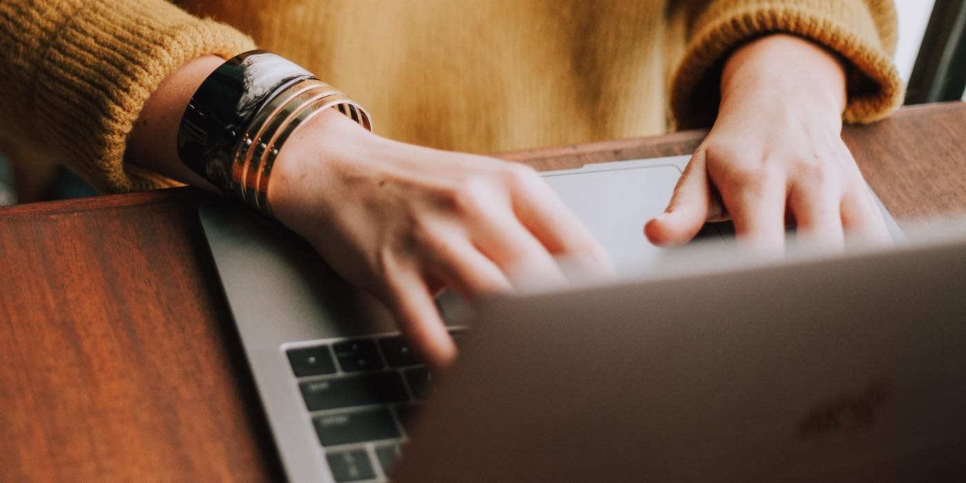 Photo of a person typing on their MacBook keyboard