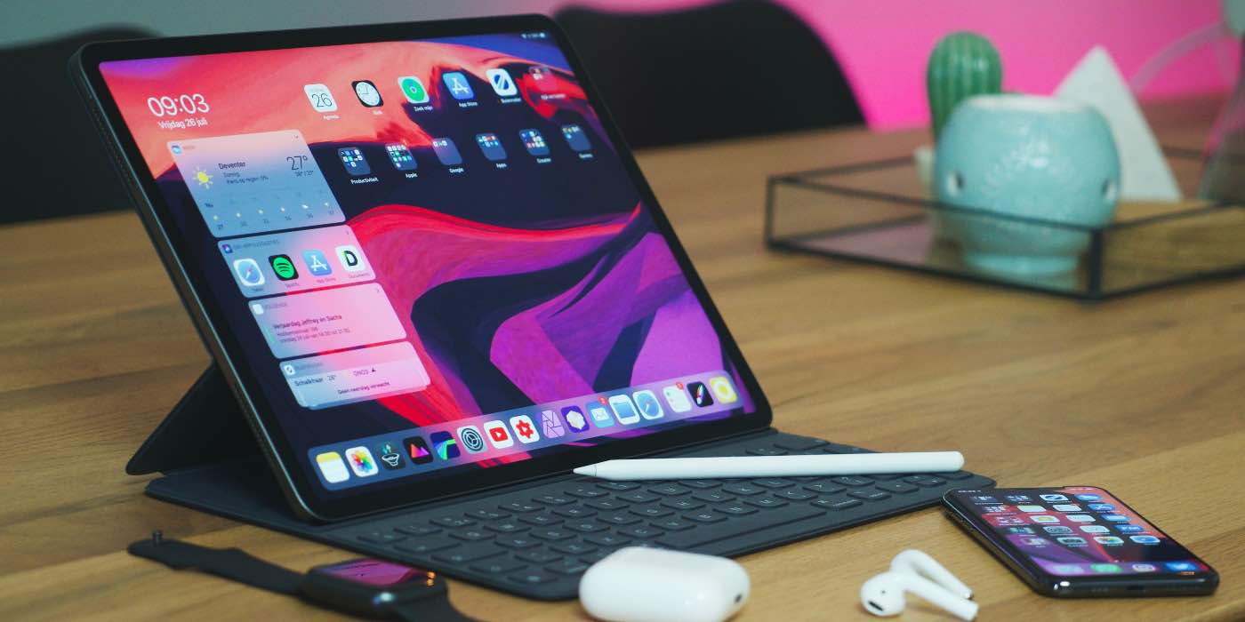 Photo of an iPad on a table with an Apple Pencil, iPhone, and AirPods