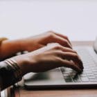 photo of a woman typing on a macbook
